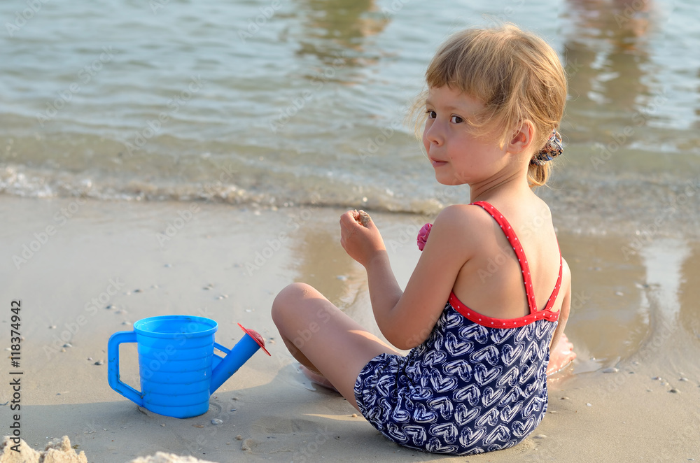 Charming little girl in a swimsuit playing on the sandy beach. Charming little girl in a swimsuit playing on the sandy beach.