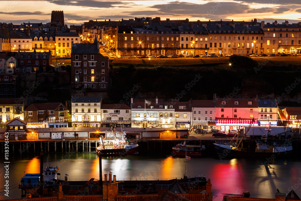 WHITBY, NORTH YORKSHIRE - AUGUST 12: Whitby harbour and town, at night, with a dramatic sunset behind. In Whitby, North Yorkshire, England. On 12th August 2016.