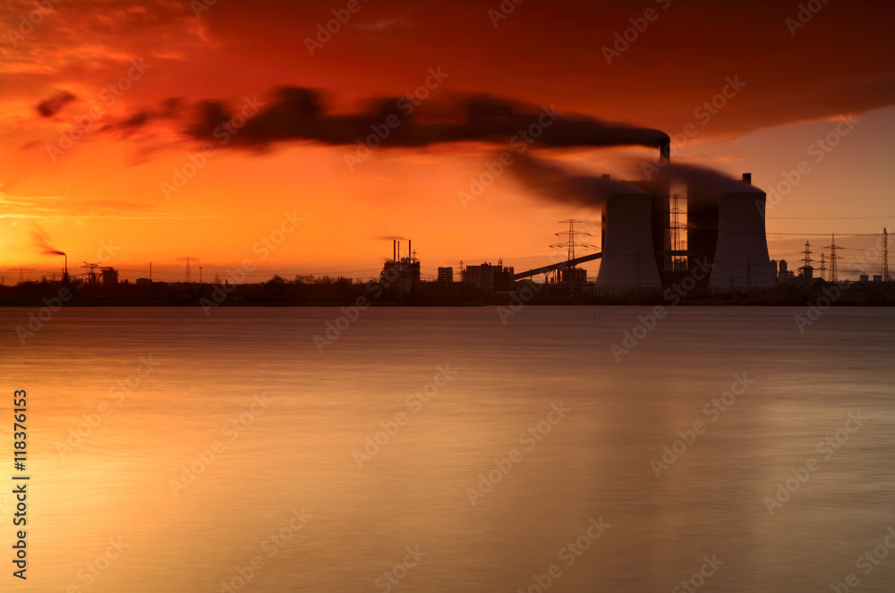 Coal Power Plant on a Lake at Sunrise, Exhaust Fumes blown by Storm, long exposure