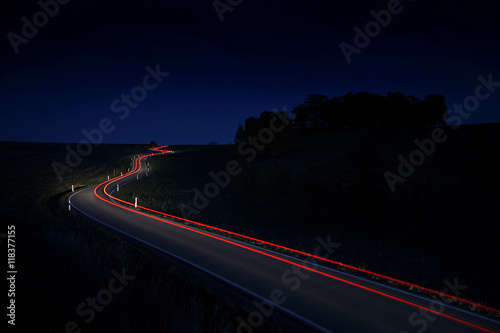 Tableau sur toile Car Driving Down a Winding Country Road, long exposure, Taillights in blurred mo