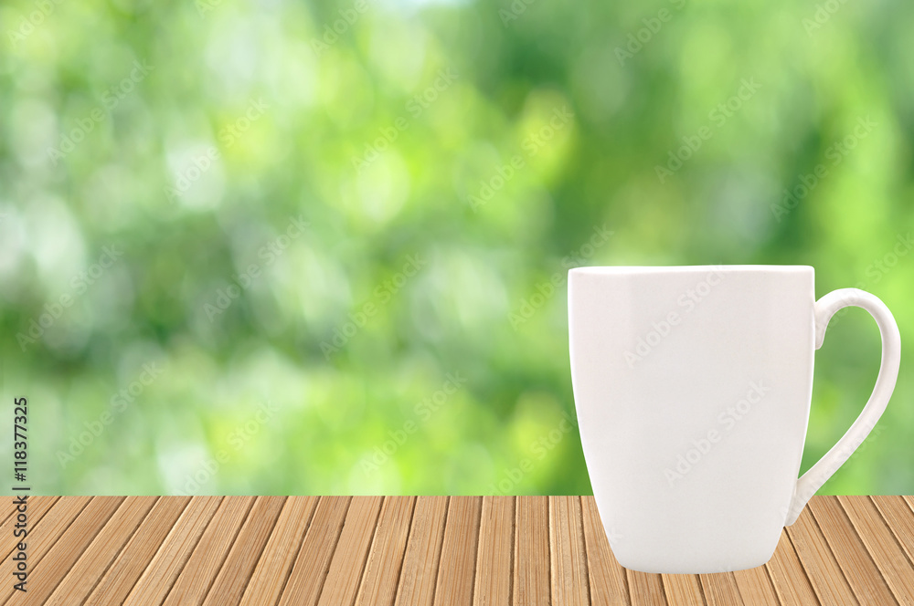 White cup on wood table with garden bokeh outdoor theme backgrou White cup on wood table with garden bokeh outdoor theme backgrou