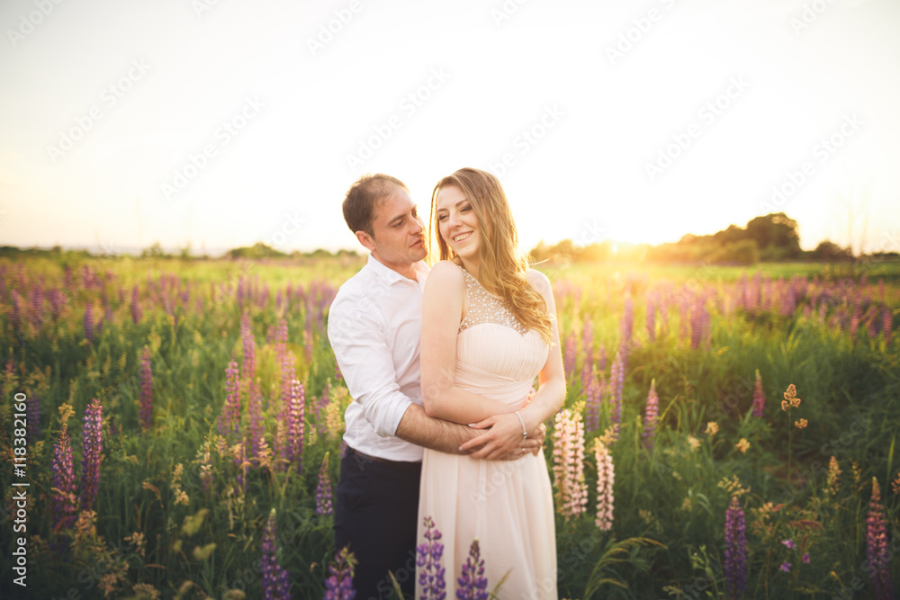 Emotional beautiful bride hugging newlywed groom from behind sunset at a field closeup Emotional beautiful bride hugging newlywed groom from behind sunset at a field closeup