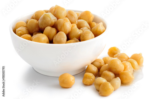 Cooked chickpeas in white bowl on white. Spilled chickpeas.