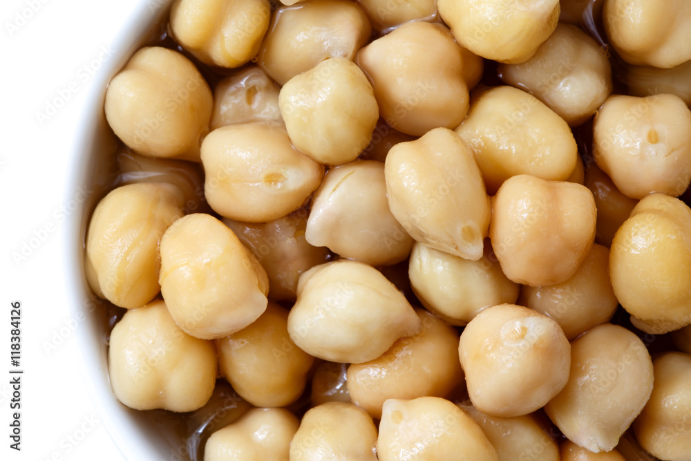Detail of cooked chickpeas in white bowl on white from above. Detail of cooked chickpeas in white bowl on white from above.