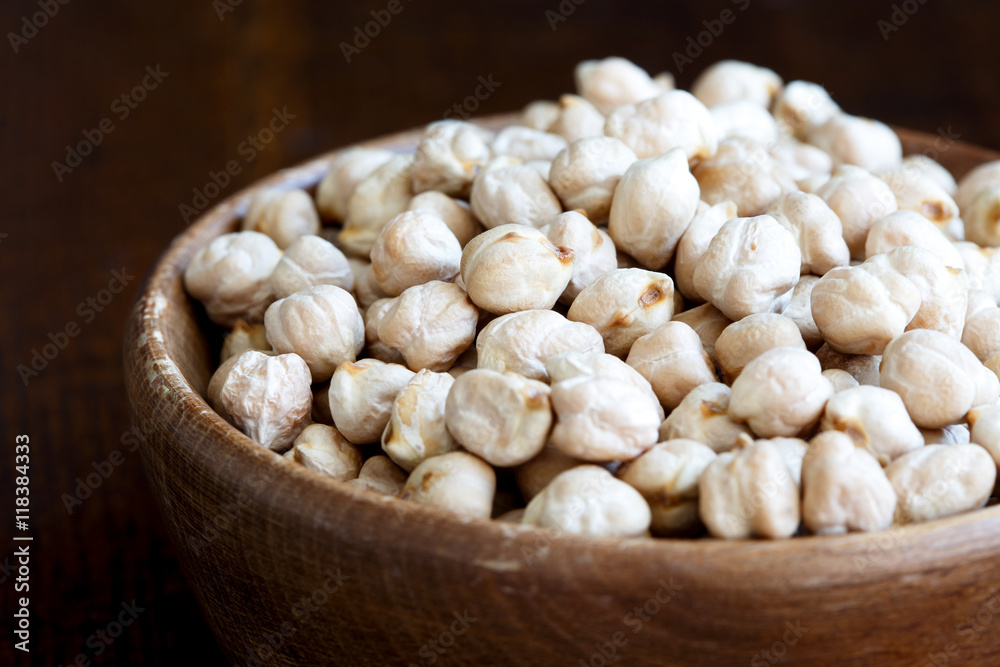 Detail of dried chickpeas in brown wooden bowl on dark. Detail of dried chickpeas in brown wooden bowl on dark.
