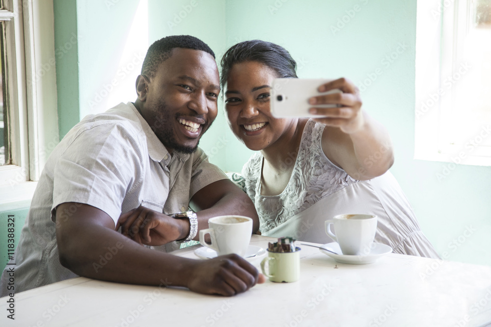 Smiling couple taking cell phone selfie at table Smiling couple taking cell phone selfie at table