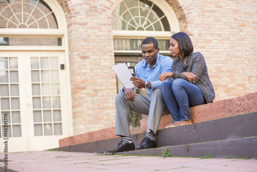 Couple sitting on steps reading paperwork Couple sitting on steps reading paperwork