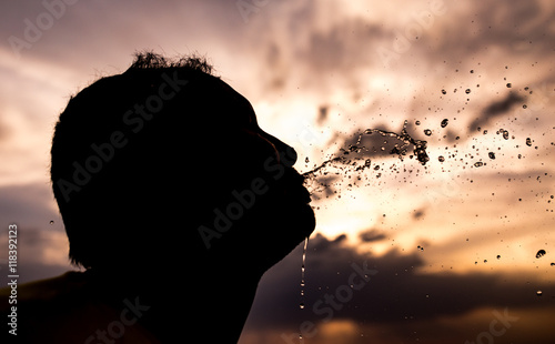 man sprinkles water at sunset