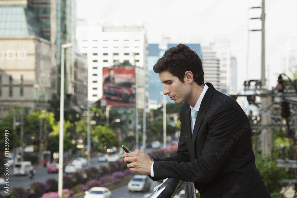 Caucasian businessman text messaging on cell phone outdoors Caucasian businessman text messaging on cell phone outdoors