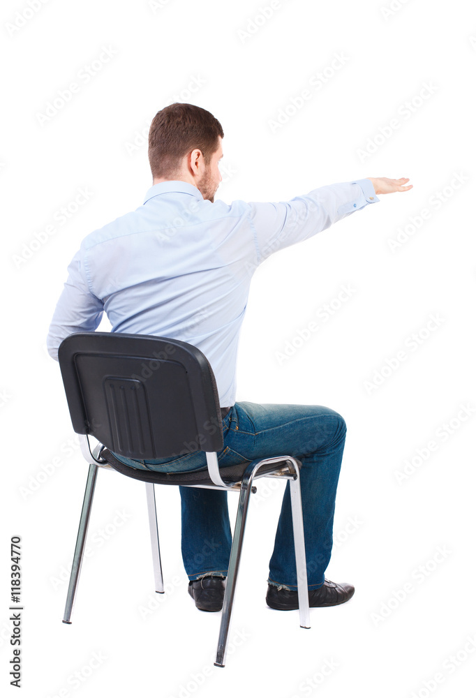 back view of young business man sitting on chair and pointing. Rear view people collection. Bearded businessman sitting on a chair and shows his hand forward. back view of young business man sitting on chair and pointing. Rear view people collection. Bearded businessman sitting on a chair and shows his hand forward.