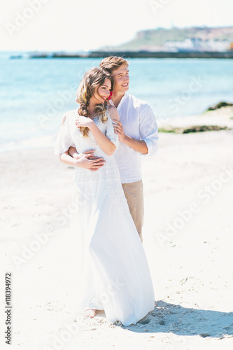 Groom holding in arms bride by the sea