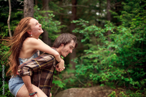 Man carrying girlfriend piggyback in forest photo