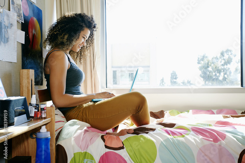 Mixed race college student using laptop in dorm photo