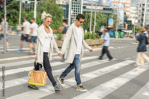 Fashionable couple crossing road at pedestrian zebra crossing