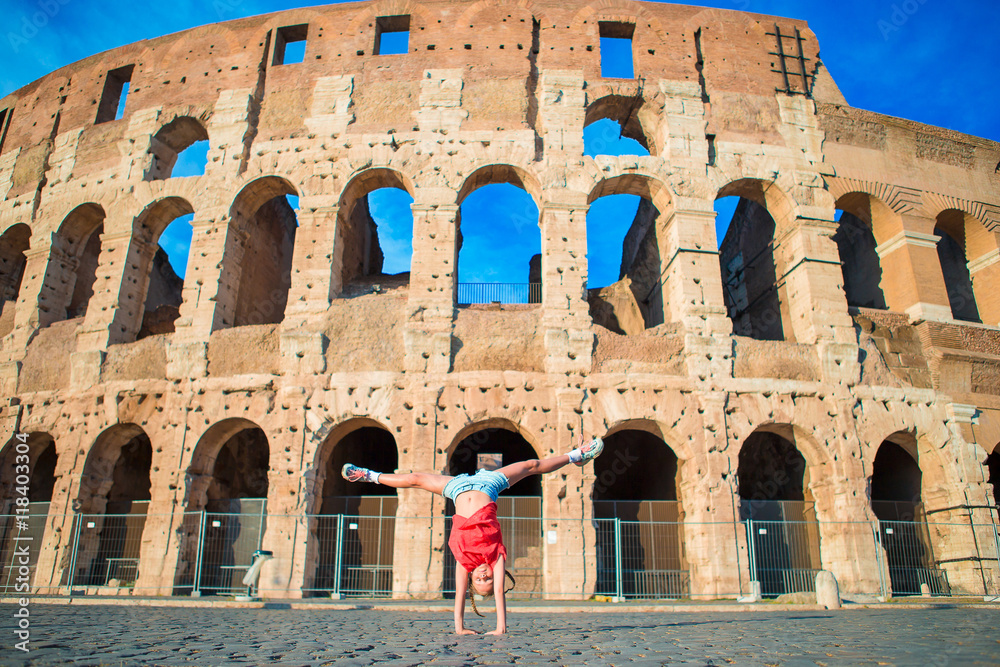 Adorable little active girl having fun in front of colosseum in rome, italy