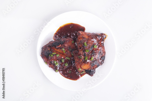 Grilled chicken or ayam golek on white plate, white background.