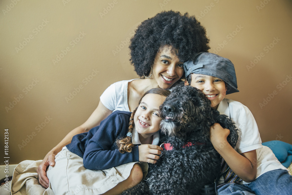 Mixed race mother and children hugging dog Mixed race mother and children hugging dog