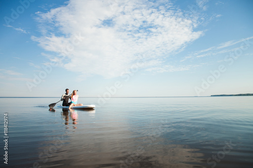 Young couple paddling on sup board