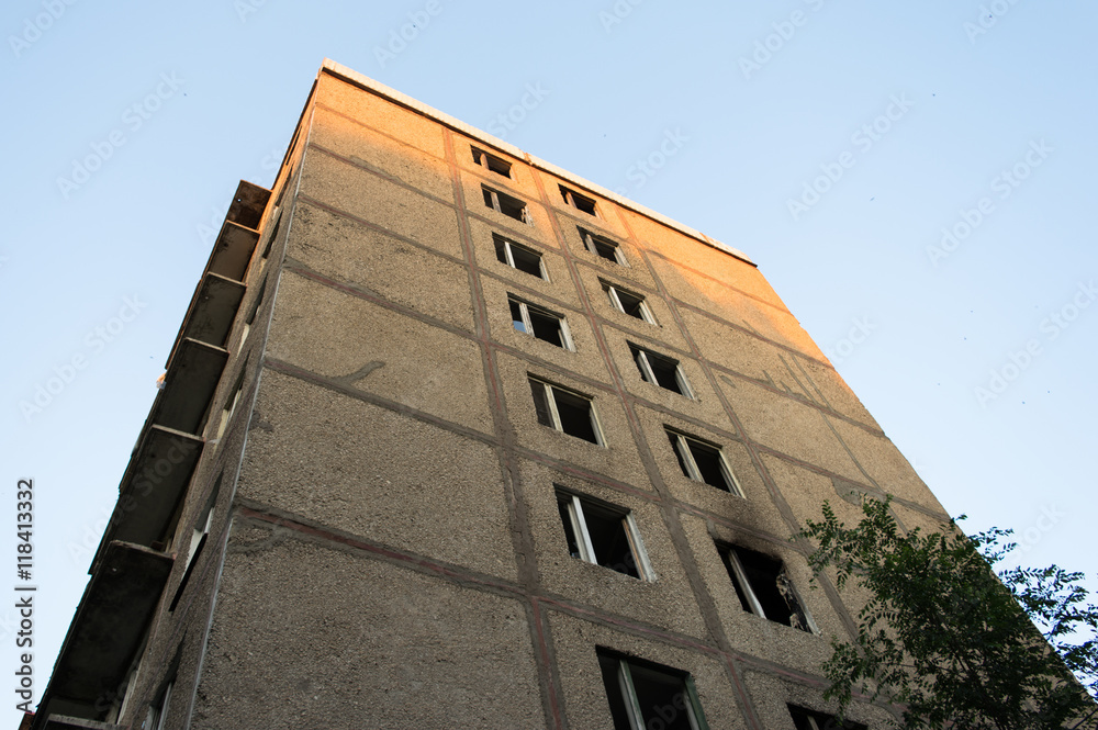 Corner of an abandoned multistory building. Broken windows, wood. Outdoor, sky. Urban. Corner of an abandoned multistory building. Broken windows, wood. Outdoor, sky. Urban.