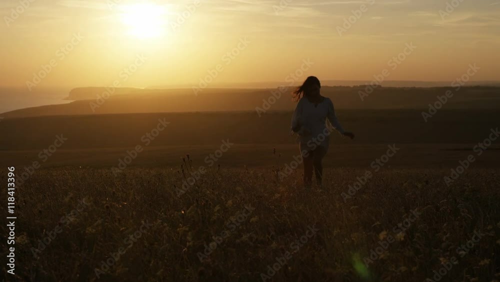 Young woman runs with her teddy bear in a field with the sunset behind her, in slow motion Young woman runs with her teddy bear in a field with the sunset behind her, in slow motion