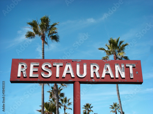aged and worn vintage photo of neon restaurant sign with palm trees