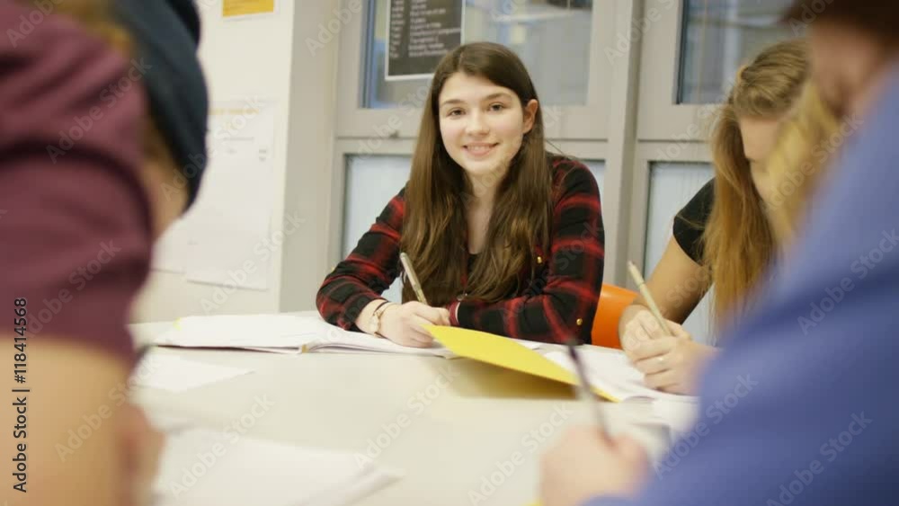 Portrait of smiling girl writing at her desk in school classroom Portrait of smiling girl writing at her desk in school classroom