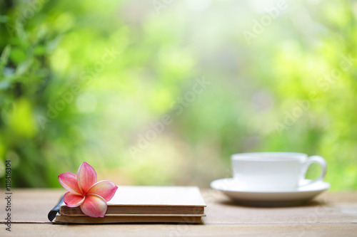 Notebook with flower and cup on wooden table 