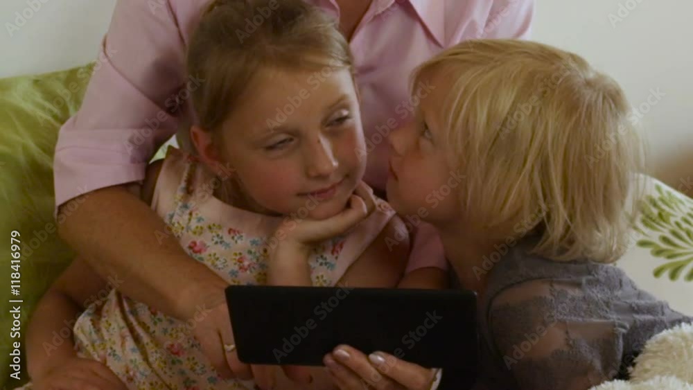Senior woman with grandkids playing with touchpad sitting on couch in living room Senior woman with grandkids playing with touchpad sitting on couch in living room