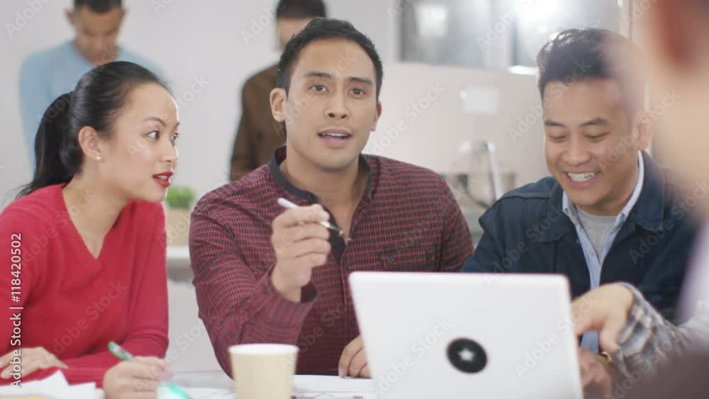 Attractive casual business group looking at laptop & brainstorming for ideas Attractive casual business group looking at laptop & brainstorming for ideas