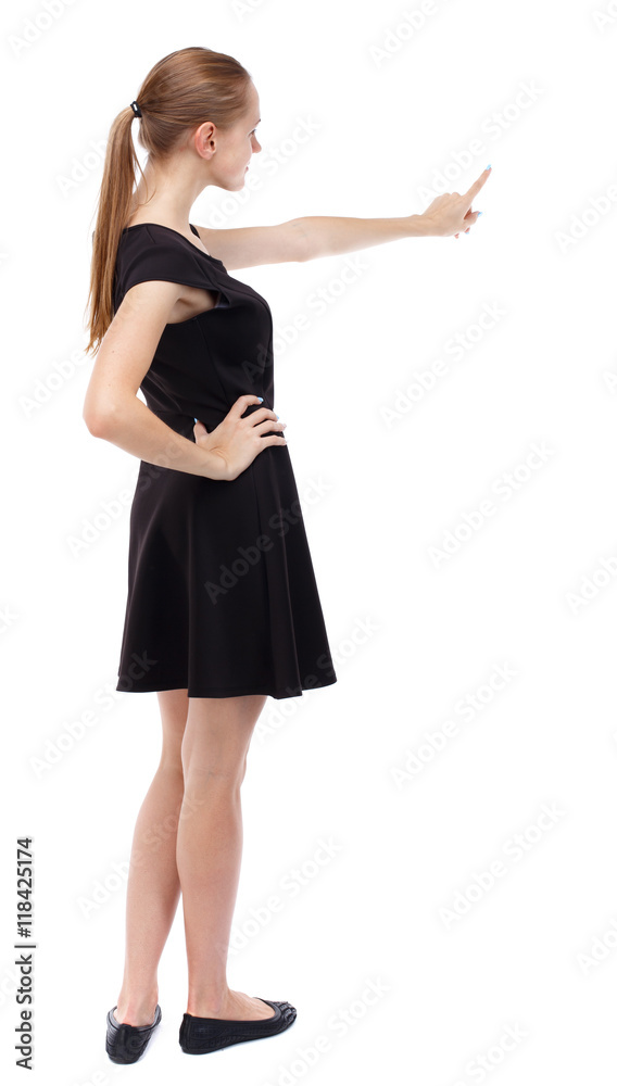 Back view of  pointing woman. beautiful girl. Rear view people collection.  backside view of person.  Isolated over white background. Blonde in a short black dress pointing her finger.