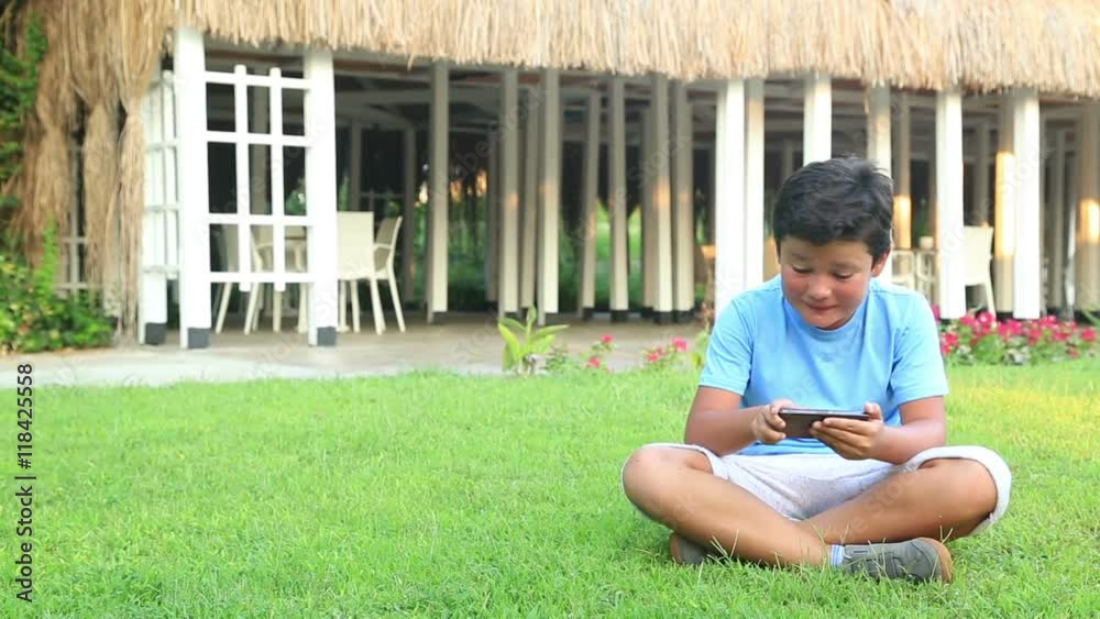 Young boy playing internet with mobile smartphone on grass. Smartphone addiction Young boy playing internet with mobile smartphone on grass. Smartphone addiction