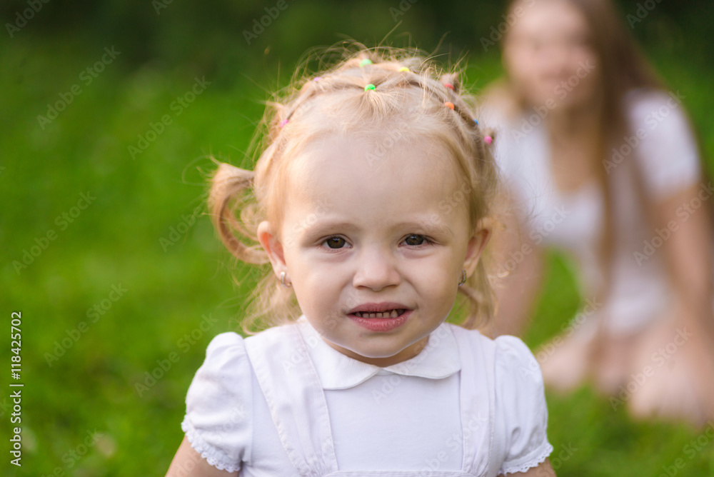 Little girl in the park and mother on blurred background Little girl in the park and mother on blurred background