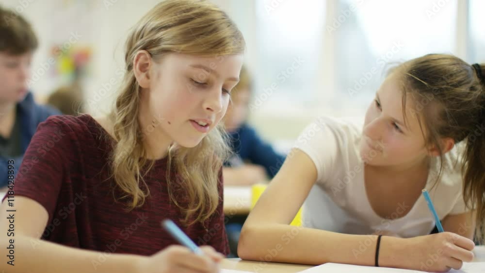 Portrait of young girls writing at their desks in school classroom Portrait of young girls writing at their desks in school classroom