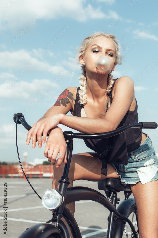 Obraz premium Pretty blonde woman with bicycle in city