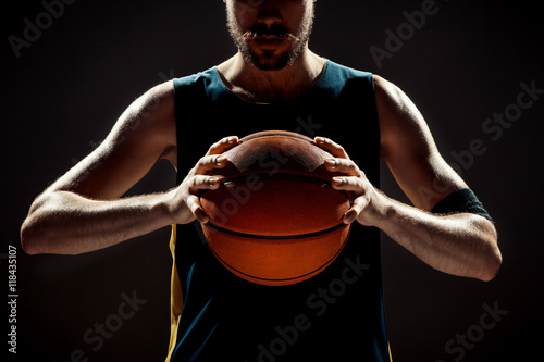 Silhouette view of a basketball player holding basket ball on black background © master1305