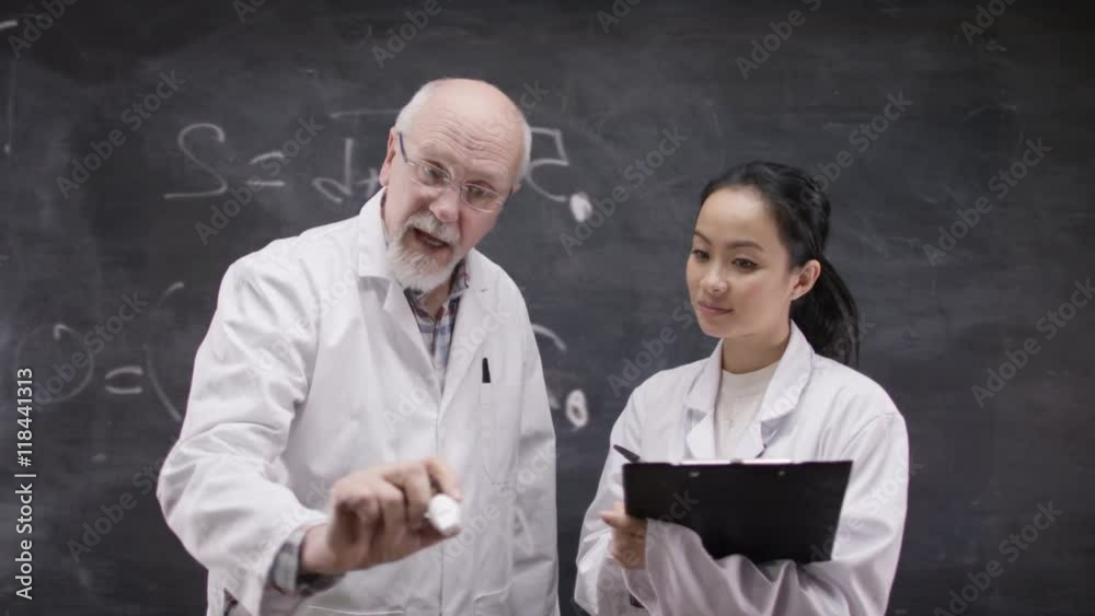  Man & little boy with tablet computer writing math sum on blackboard