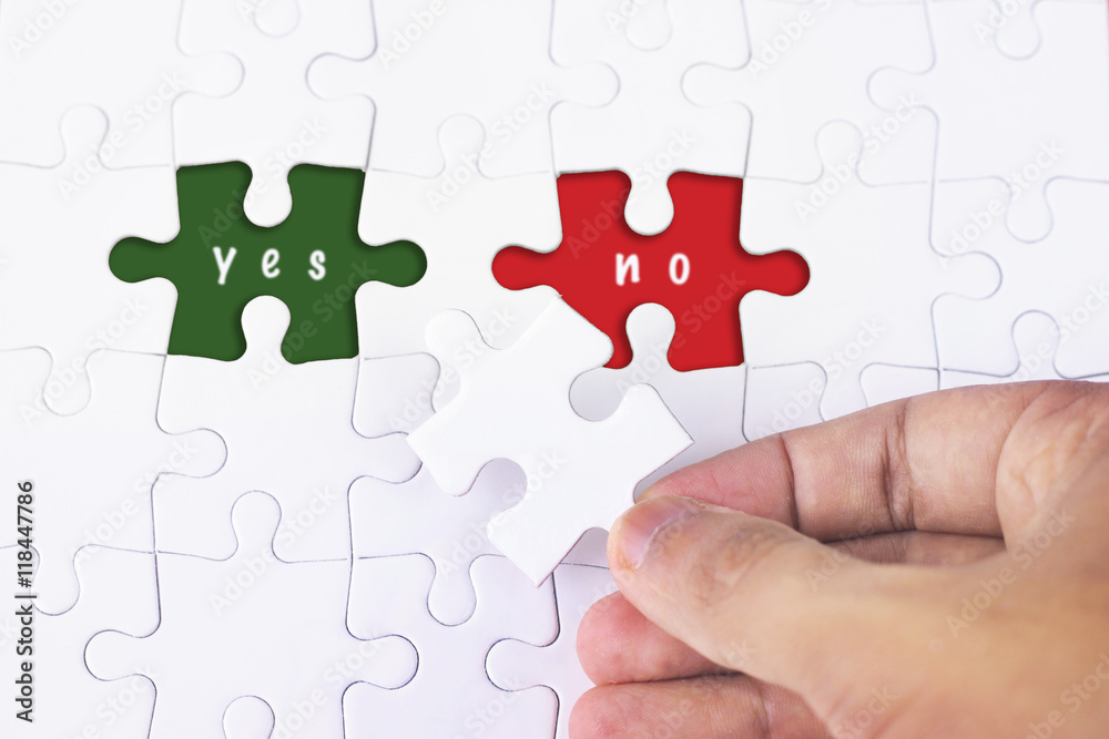 Business Concept - Female hand and missing puzzle with Yes and NO WORD Business Concept - Female hand and missing puzzle with Yes and NO WORD