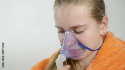 Teenage girl using nebulizer with breathing mask at home inhaling the medication during the nebulizer treatment for asthma or respiratory infection and pulmonary disorder photo