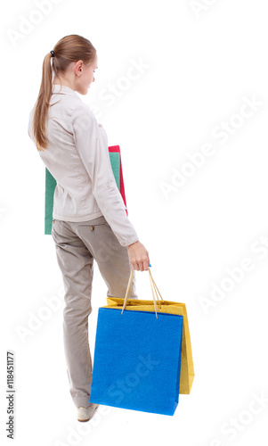 back view of woman with shopping bags. backside view of person. Rear view people collection. Isolated over white background. Skinny girl in white denim suit standing with paper bags.