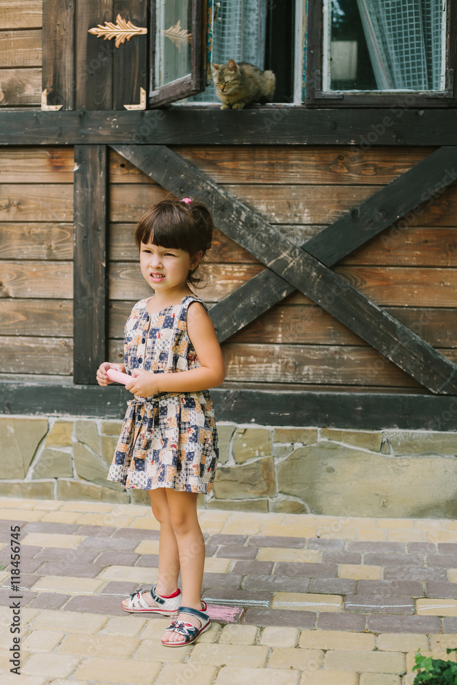 girl standing with chalk near a wooden house girl standing with chalk near a wooden house
