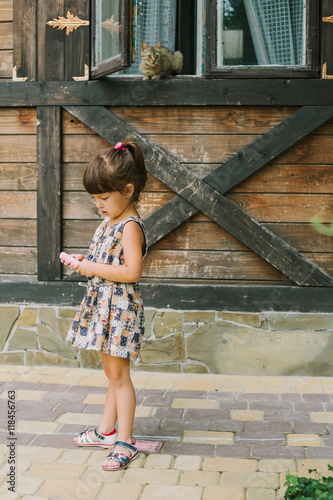 girl standing with chalk near a wooden house