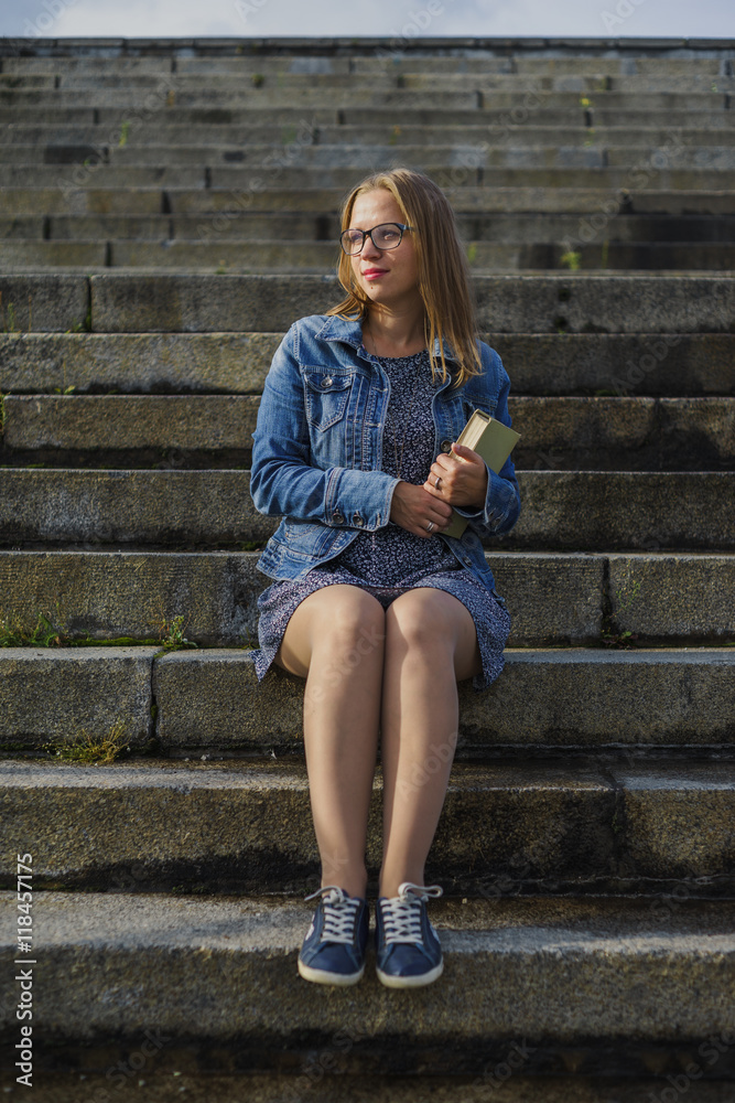 Female student sitting on stairs with book Female student sitting on stairs with book
