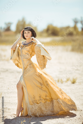 Beautiful woman like Egyptian Queen Cleopatra on in desert outdoor. photo