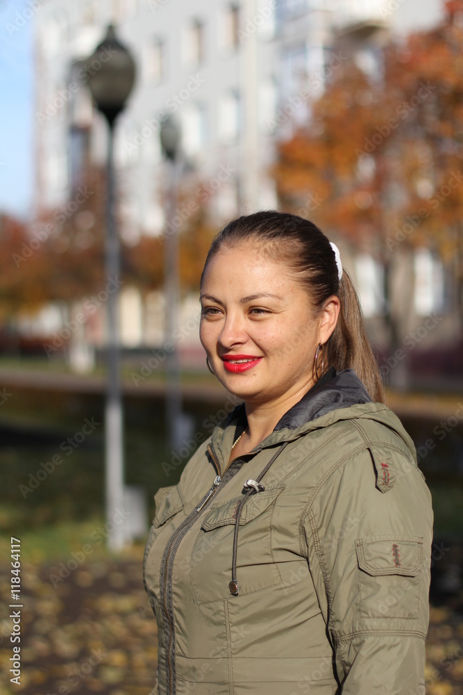 Portrait of a young cheerful chubby woman in a raincoat on the street in autumn Portrait of a young cheerful chubby woman in a raincoat on the street in autumn