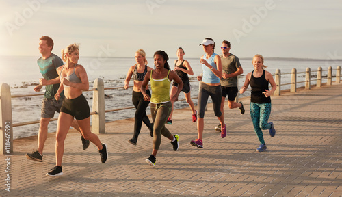 Runners running on street by the seaside
