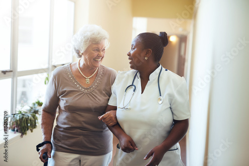 Fototapeta Nurse assisting senior woman at nursing home