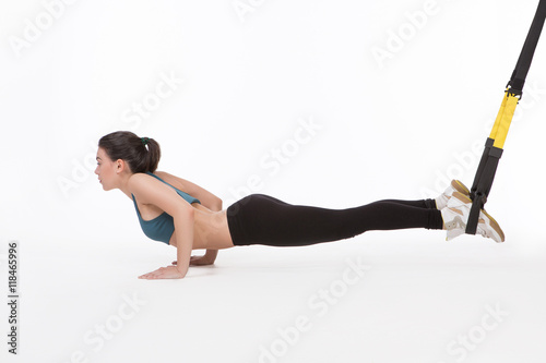 Core body excercise concept. Lady posing for photographer in studio. Beautiful lady training with suspension trainer sling or suspension straps.