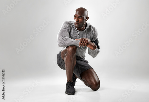 Fototapeta Handsome african man kneeling on grey background