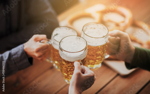 Fototapeta close up of hands with beer mugs at bar or pub