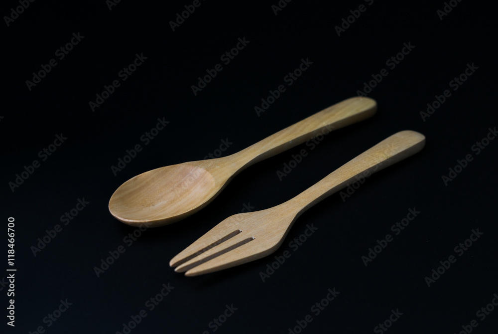 Handcrafted wooden kitchen utensils with a fork and spoon isolated on black background Handcrafted wooden kitchen utensils with a fork and spoon isolated on black background